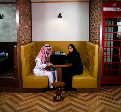 Two professionals engage in a focused discussion within a private booth at a Servcorp coworking space in Saudi Arabia.