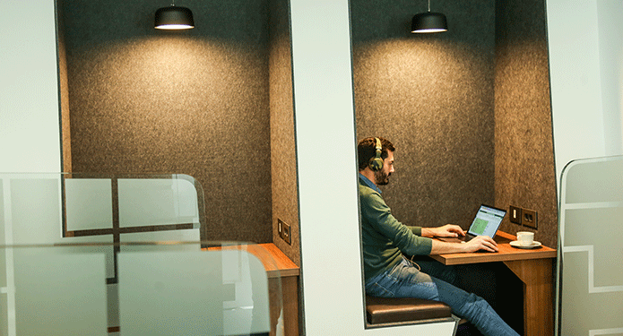 Client is focusing on his work at his dedicated desk in a professional coworking space environment.