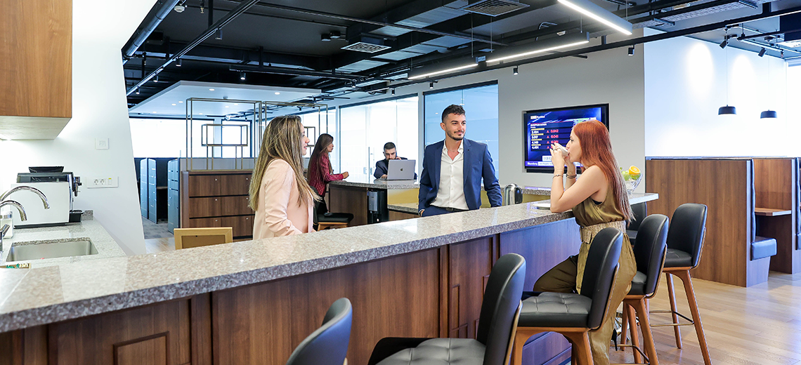 Coworking Space at Qubic Square with people networking and collaborating in a fully-stocked kitchen.